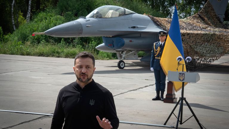 Ukraine's President Volodymyr Zelenskyy answers media questions standing against the background of Ukraine's Air Force's F-16 fighter jets in an undisclosed location in Ukraine, Sunday, Aug. 4, 2024. The F-16 fighter jets that have been delivered to Ukraine by Western countries will be flying sorties in Ukrainian skies and helping the country's current fleet of Soviet-era jets to counter Russia's invasion. (AP Photo/Efrem Lukatsky)