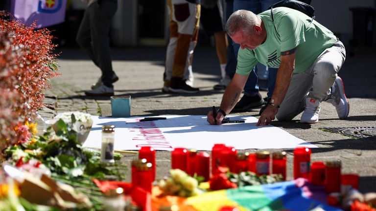 A man writes a message on a placard following an incident in which several individuals were killed after a man randomly stabbed passers-by with a knife at a city festival, in Solingen, Germany, August 24, 2024. REUTERS/Thilo Schmuelgen