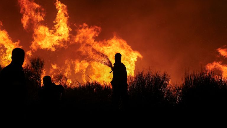 Firefighters try to extinguish a wildfire burning in Dionysos, Greece.
Pic: Reuters