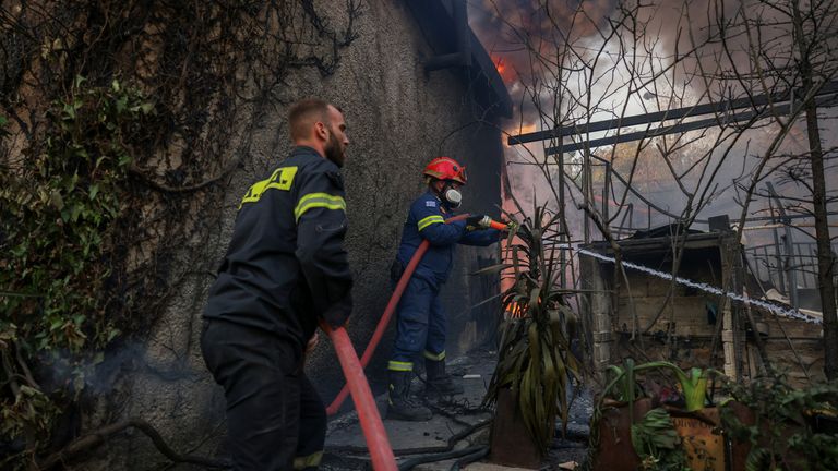 Firefighters try to extinguish a wildfire burning a house in Dionysos, Greece.
Pic: reuters