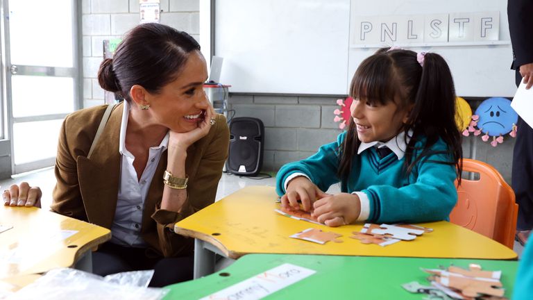 Meghan sits with a schoolgirl at the Colegio La Giralda. Pic: Le Studio Photography 