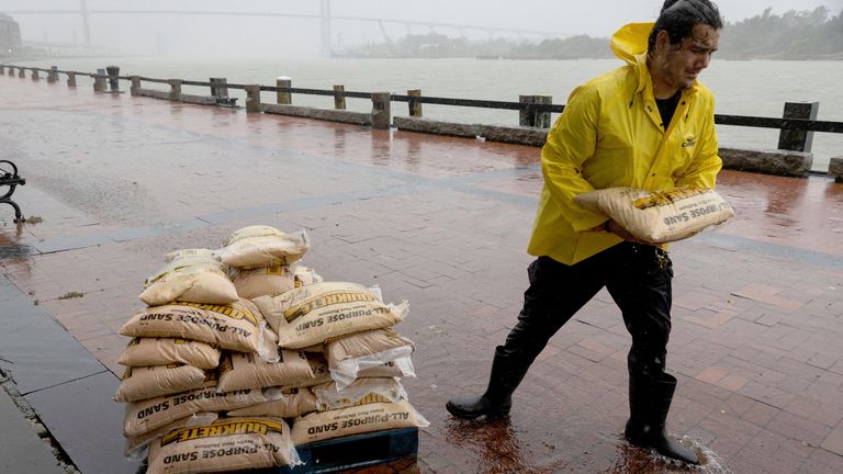 A worker moves sandbags in the rain at River Street as Tropical Storm Debby moves towards Georgia, in Savannah, Georgia, U.S., August 5, 2024. REUTERS/Marco Bello 