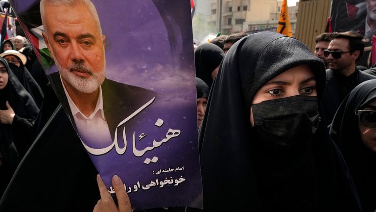 A woman holds up a poster of Haniyeh during his funeral ceremony. Pic: AP