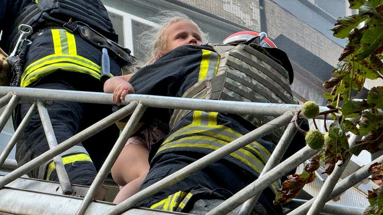 Firefighters rescue a girl from the residential building hit in Kharkiv. Pic: Reuters