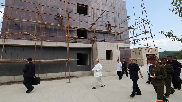 Kim Jong Un walks past workers on scaffolding, during a visit to the construction sites.
Pic: KCNA