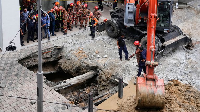 Fire and Rescue department use crane to dig after receiving reports that a woman has fallen into the sinkhole after a section of the sidewalk caved in Kuala Lumpur, Friday, Aug. 23, 2024. (AP Photo/Vincent Thian)