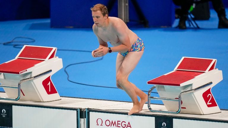 A lifeguard jumps into the competition pool to retrieve United States swimmer Emma Webber's swimming cap that happened to have been left at the bottom of the pool during the morning session at the 2024 Summer Olympics, Sunday, July 28, 2024, in Nanterre, France. (AP Photo/Petr David Josek)