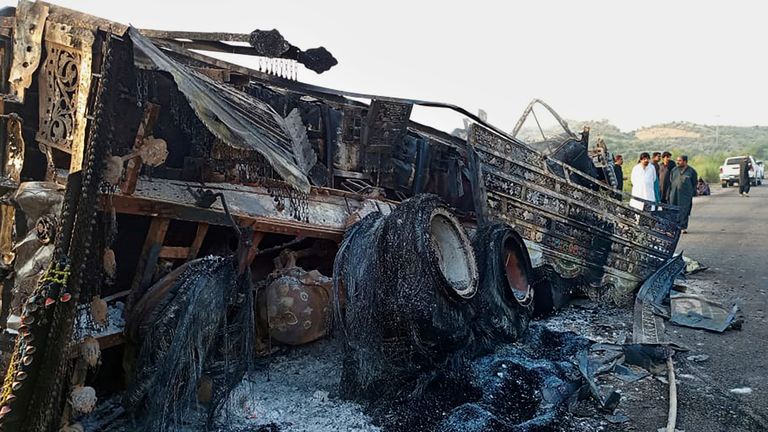 People look at a burnt vehicle which was torched by gunmen after they killed passengers at a highway in Musakhail, a district in Baluchistan province in restive southwestern Pakistan, Monday, Aug. 26, 2024. (AP Photo/Rahmat Khan)