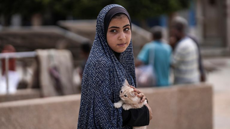 A Palestinian girl carries her cat as she evacuates a school that had been her shelter, in eastern Deir al-Balah, Gaza Strip. Pic: AP