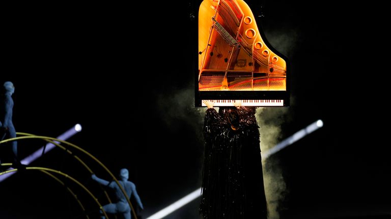 Alain Roche plays on a piano suspended vertically in the air during the closing ceremony. Photo: Reuters