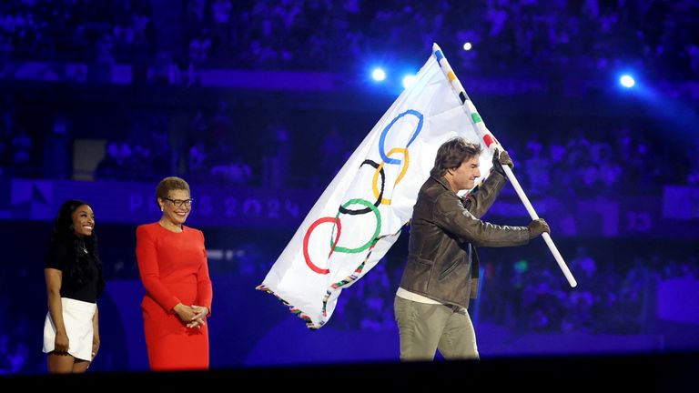 Actor Tom Cruise holds the Olympic flag during the closing ceremony as the Mayor of Los Angeles Karen Bass and Simone Biles of United States look on. Pic: Reuters