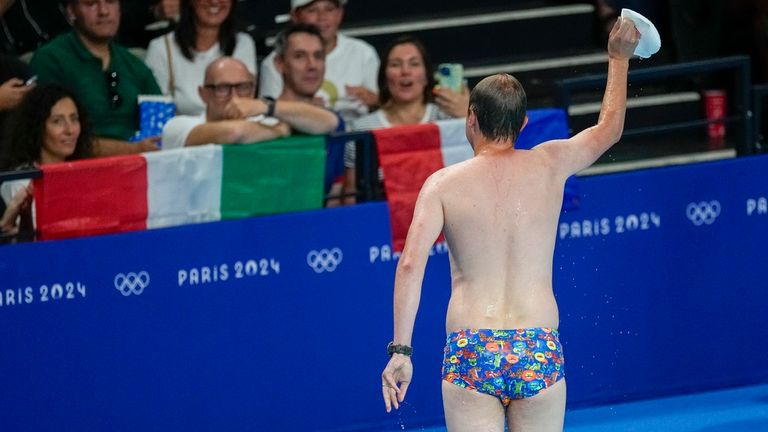 A lifeguard gestures to the crowd after retrieving United States swimmer Emma Webber's swimming cap that happened to have been left at the bottom of the pool during the morning session at the 2024 Summer Olympics, Sunday, July 28, 2024, in Nanterre, France. (AP Photo/Petr David Josek)