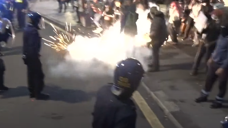 A firework goes off at the feet of counter-protesters in Plymouth. 