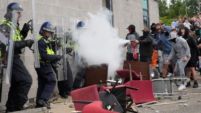 A protester uses a fire extinguisher on police officers as trouble flares during an anti-immigration protest outside the Holiday Inn Express in Rotherham, South Yorkshire. Picture date: Sunday August 4, 2024.

