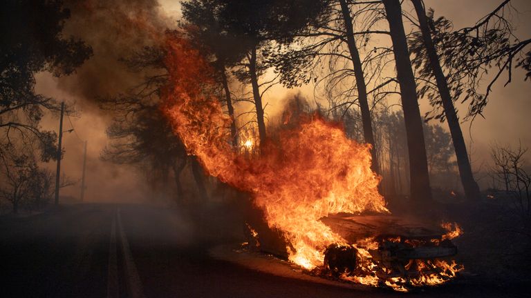 A car burns in Varnava village during a wildfire, north of Athens, Greece, Sunday, Aug. 11, 2024, with many regions of the country on high alert due to high temperatures and wind speeds. (AP Photo/Michael Varaklas)