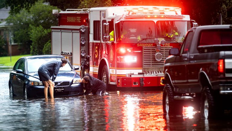People attach a towline to a stranded vehicle on a flooded street in Savannah, Georgia. Pic: AP