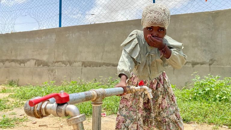 A young girl drinks from a tap at the camp. Pic: Sky News