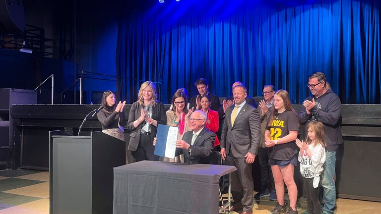 Tim Walz beams while holding up the so-called Taylor Swift bill he signed into law. Pic: AP