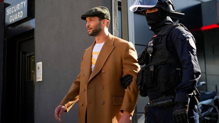 Tristan Tate is lead out of a property on the outskirts of Bucharest after it was raided. Pic: AP