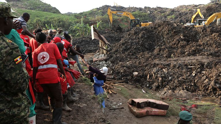 Onlookers watch as workers search for survivors at the site of a collapsed landfill in Kampala, Uganda, Sunday, Aug. 11, 2024. (AP Photo/Hajarah Nalwadda)