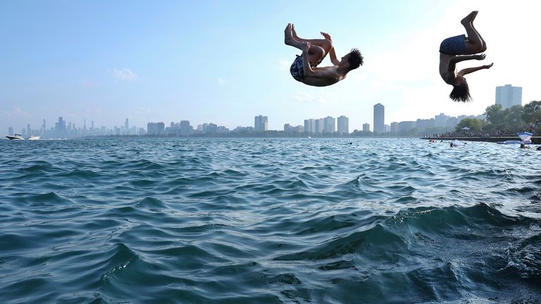 Two teenagers plunge into Lake Michigan as people cool off during a heat wave at Montrose Beach in Chicago, Tuesday, Aug. 27, 2024. (Chris Sweda/Chicago Tribune via AP)