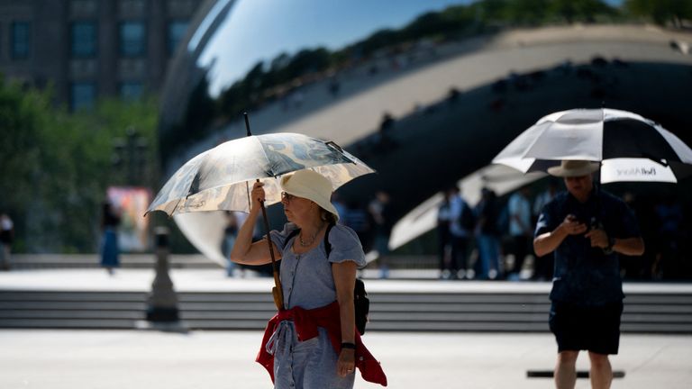 A woman uses an umbrella to shield herself from the sun during a period of hot weather in Chicago, Illinois, U.S. August 26, 2024. REUTERS/Vincent Alban