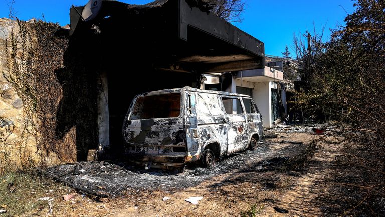 A destroyed vehicle is seen at the yard of a burned house as a wildfire burns near the village of Varnava.
Pic: Reuters