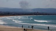 People spend time at the beach as smoke billows over southern Lebanon amid the cross-border clashes. Pic: Reuters