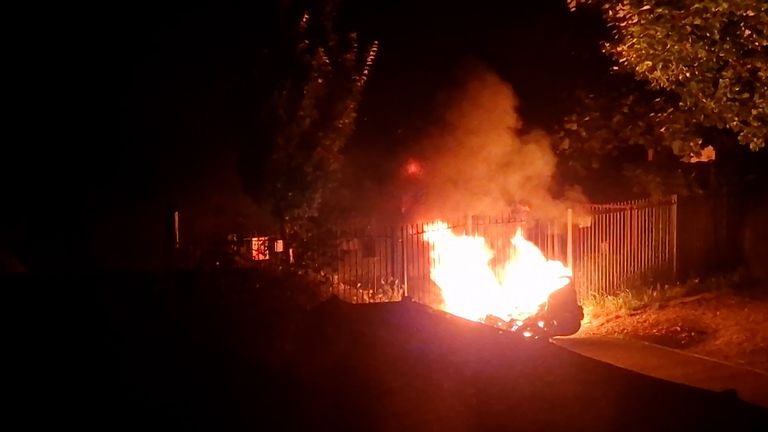 A motorcycle on fire in the park outside Paul's house