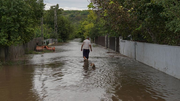 A man walks a flooded road in Slobozia Conachi, Galati country, Romania. Pic: Reuters