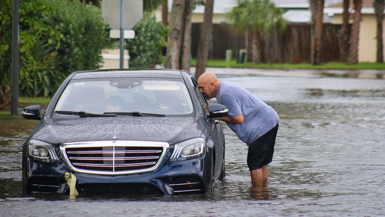 Melvin Juarbe, right, attempts to assist an unidentified driver whose car stalled in floodwaters from Hurricane Helene Thursday, Sept. 26, 2024 in Madeira Beach, Fla. The men tried to pull the car to dry land with their pickup truck but have opted to call AAA after several failed attempts. (Max Chesnes/Tampa Bay Times via AP)