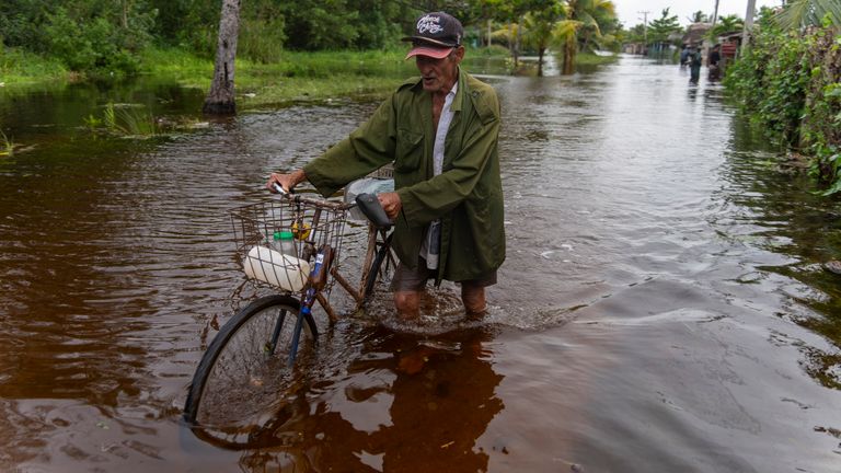 A man pushes his bicycle through a flooded street after Hurricane Helene passed through Guanimar, Artemisa province, Cuba, Wednesday, Sept. 25, 2024. (AP Photo/Ramon Espinosa)