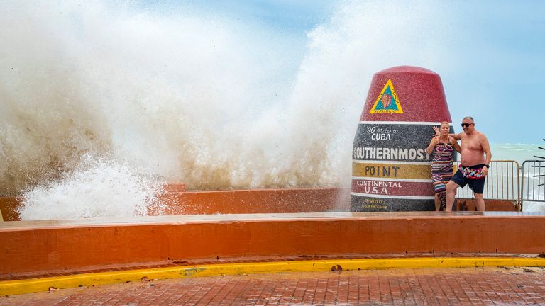 Visitors to the Southernmost Point marker in Key West, Fla., are hit by wind driven waves from approaching Hurricane Helene on Wednesday, Sept. 25, 2024. (Rob O'Neal/The Key West Citizen via AP)