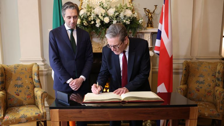 The prime minister signs the official Irish state guest house in Dublin. Pic: PA