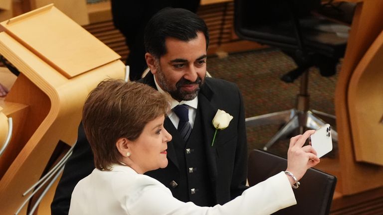 Former first ministers Nicola Strugeon and Humza Yousaf take a selfie as they await the arrival of the King. Pic: PA