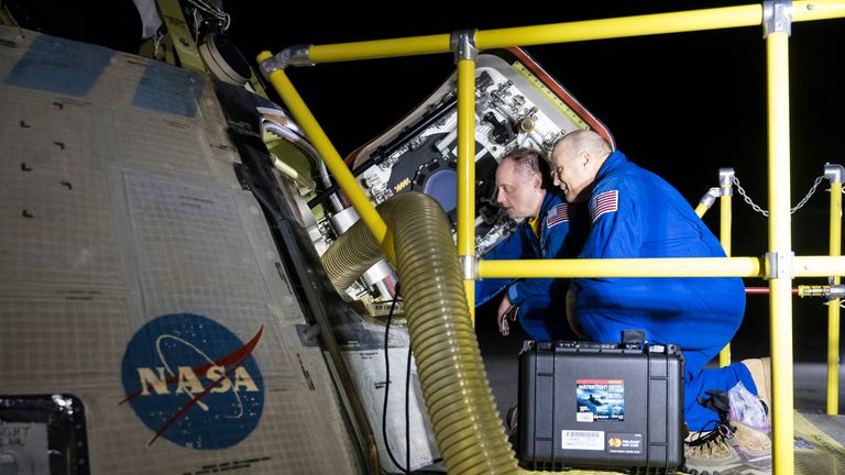 NASA astronauts Mike Fincke, left, and Scott Tingle look inside NASA's Boeing Crew Flight Test Starliner spacecraft after the empty capsule landed at White Sands Missile Range's Space Harbor, Friday, Sept. 6, 2024, in New Mexico. (Aubrey Gemignani/NASA via AP)