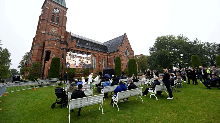 Mourners watch the funeral from outside the church. Pic: Reuters