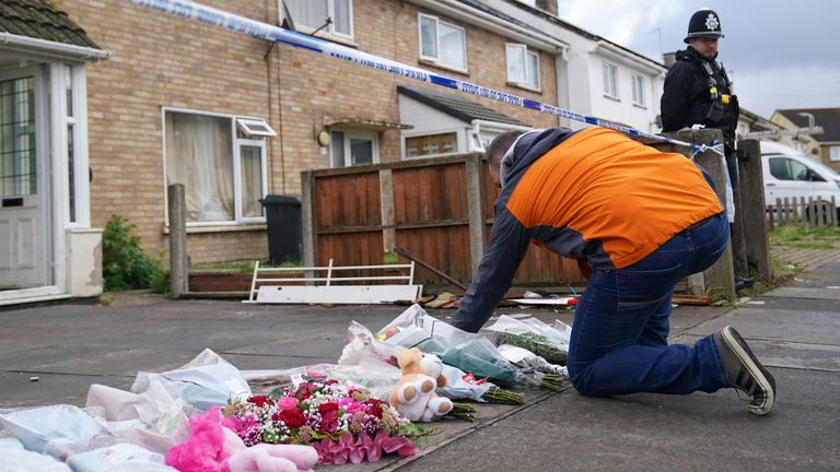 A man places a bunch of flowers amongst other tributes 
Pic: PA