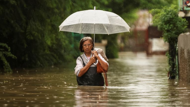 A woman wades through floodwaters as it rains during Tropical Storm Yagi, locally known as Enteng in Apalit, Pampanga, Philippines, September 5, 2024. REUTERS/Eloisa Lopez