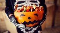 Boy in skeleton costume holding bowl full of candies 