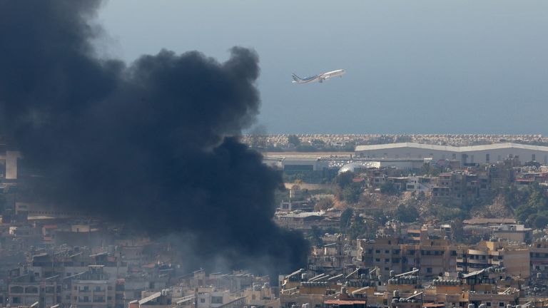 8 Ekim 2024'te Lübnan'ın Hadath kentinden görüldüğü gibi, Hizbullah ile İsrail güçleri arasında devam eden düşmanlıkların ortasında Refik Hariri Uluslararası Havalimanı'ndan bir uçak kalkarken Beyrut'un güney banliyölerinde duman yükseliyor. REUTERS/Mohamed Azakir