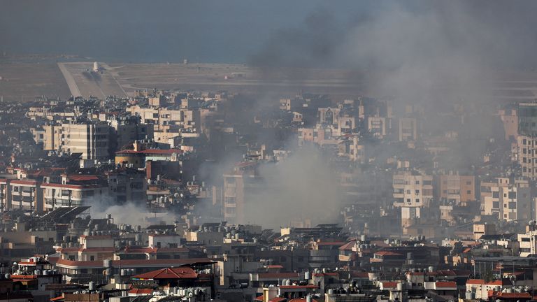 An airplane takes off at Beirut-Rafic Hariri International Airport as smoke rises over Beirut's southern suburbs after a strike, amid the ongoing hostilities between Hezbollah and Israeli forces