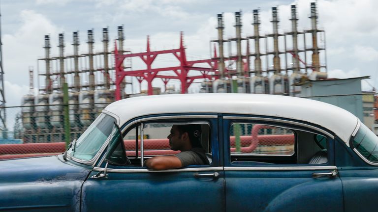 Una persona conduce un automóvil clásico estadounidense junto a un generador flotante que no produce electricidad durante varios días, en La Habana, Cuba, el viernes 18 de octubre de 2024. (Foto AP/Ramon Espinosa)