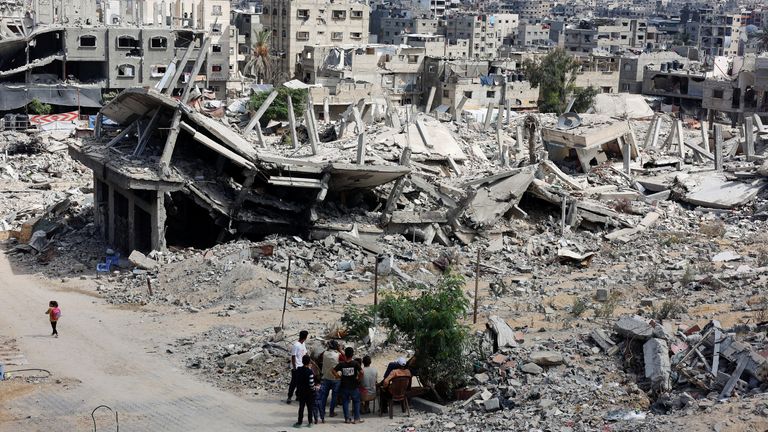 On the same day, people sit next to rubble in Khan Younis in Gaza. Pic: Reuters