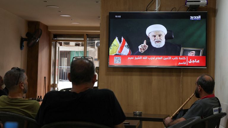 People watch Hezbollah deputy leader Sheikh Naim Qassem deliver a televised speech while sitting in a cafe in Beirut. Image: Reuters