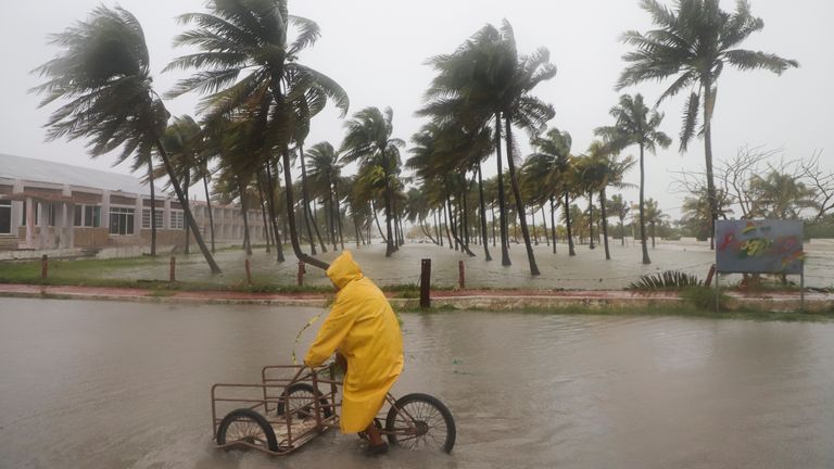 A person rides his bike through a flooded street in the rain in Progreso, Yucatan state, Mexico. Pic: AP