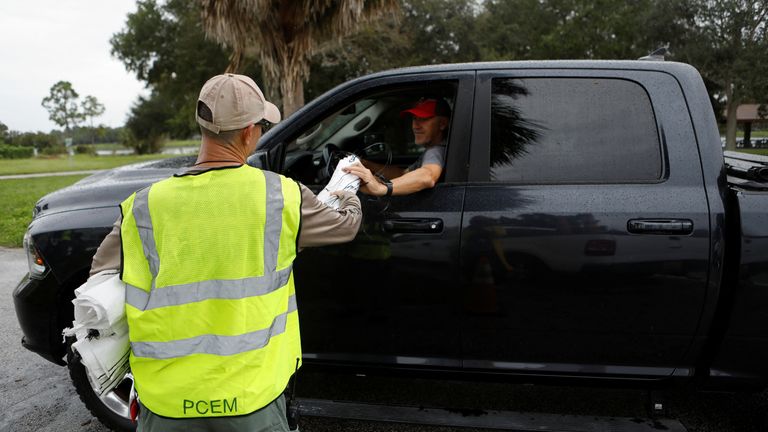 Una persona consegna sacchi vuoti a un uomo, mentre i sacchi di sabbia vengono distribuiti ai residenti della contea di Pinellas prima del previsto arrivo della tempesta tropicale Milton, a Seminole, Florida, Stati Uniti, il 6 ottobre 2024. REUTERS/Octavio Jones