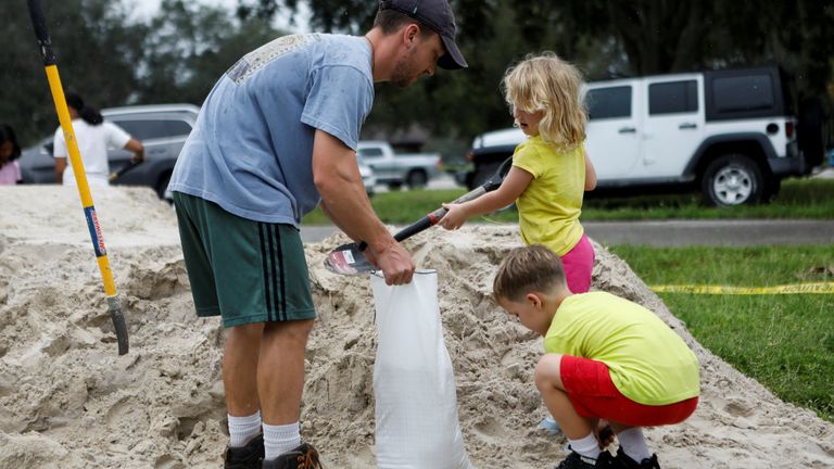 Tom Murphy prepares a sandbag with children, as sandbags are distributed to Pinellas County residents before the expected arrival of Tropical Storm Milton, in Seminole, Florida, U.S. October 6, 2024. REUTERS/Octavio Jones