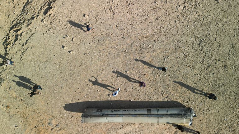 A drone view shows people stand around apparent remains of a ballistic missile lying in the desert, following an attack by Iran on Israel, near the southern city of Arad, Israel.
Pic: Reuters