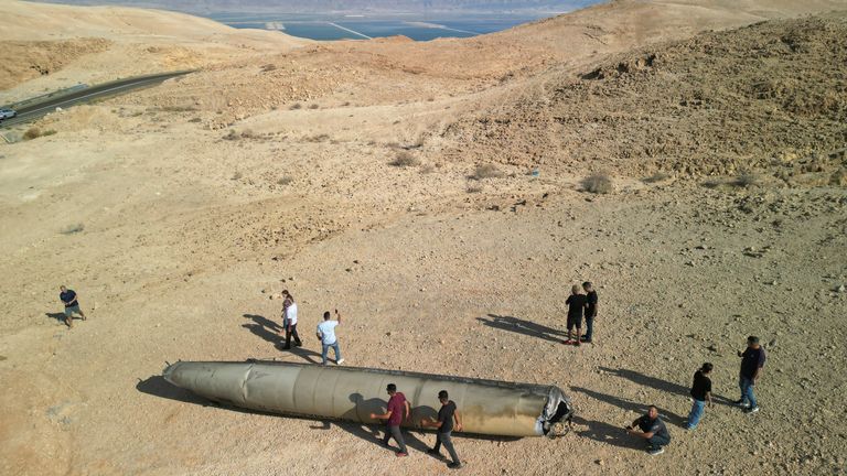 A drone view shows people stand around apparent remains of a ballistic missile lying in the desert, following an attack by Iran on Israel, near the southern city of Arad, Israel.
Pic: Reuters